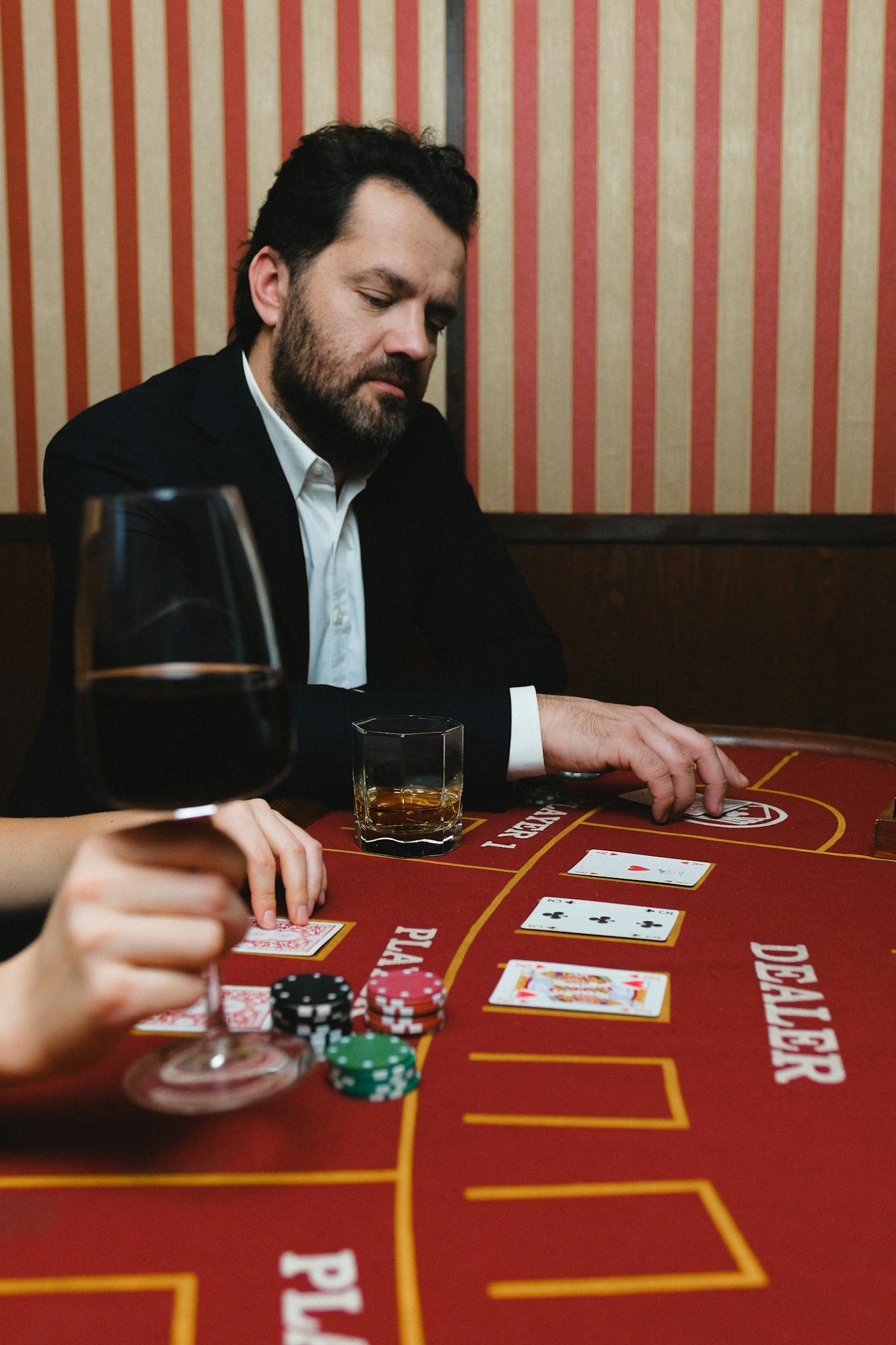 Home A man concentrating on a poker game at a casino table with cards, chips, and drinks.